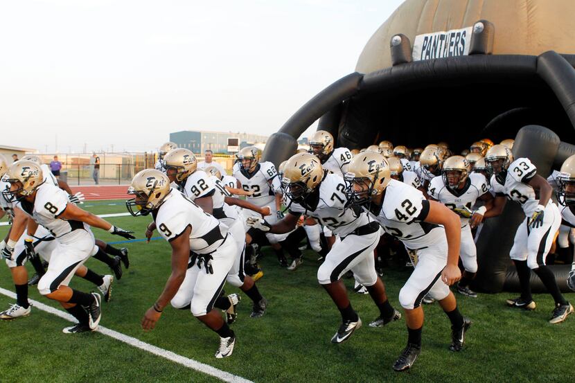 Plano East High players enter the field through their inflatable football helmet before a...