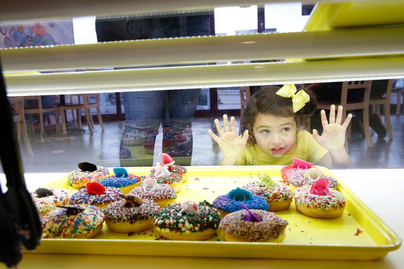 Gwendolyn Trujillo, 3, eyes the doughnuts before making a selection at the new Jarams Donuts...