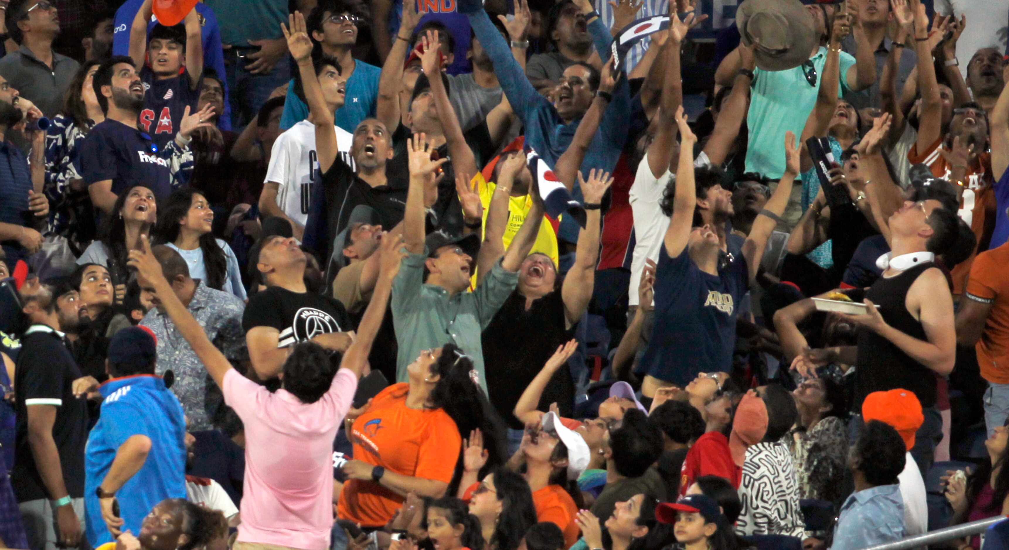 Cricket fans track a long fly ball that sailed into the stands from the wicket of a...