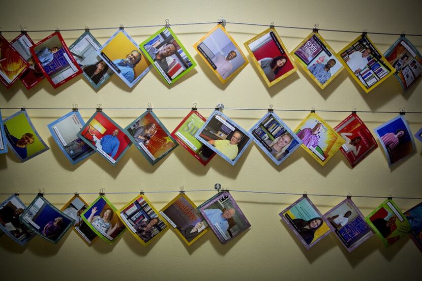 Photos of current employees at Publishing Concepts hang on a wall in a hallway at its...