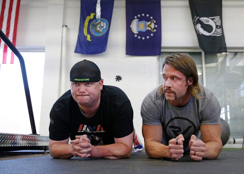 
Jacob Schick (left), an injured military veteran, works on physical training with David...