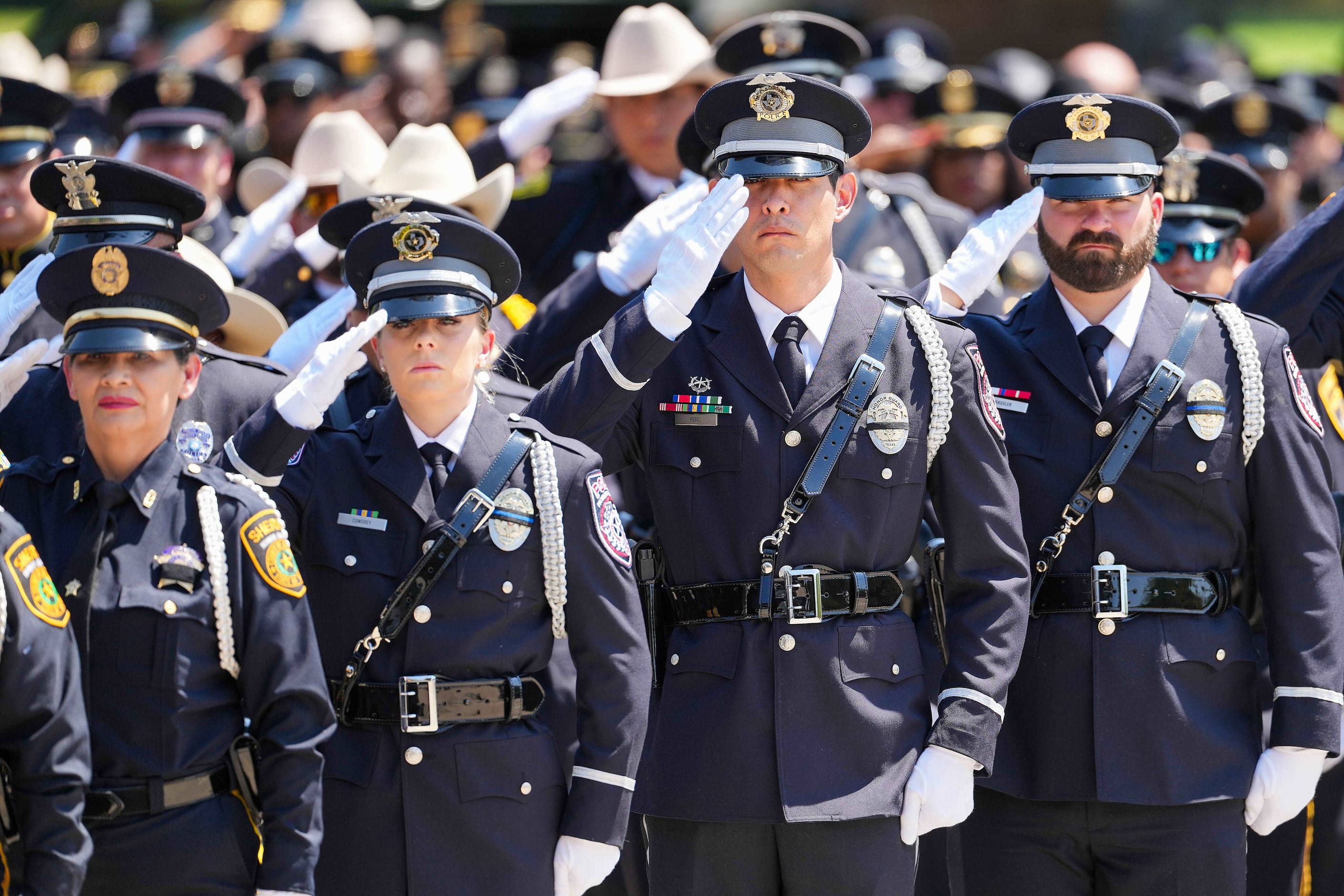 Law enforcement officers from around the state and the nation salute during honors following...