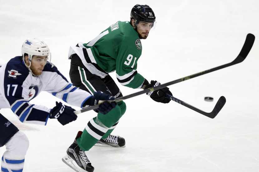 The puck passes by Winnipeg Jets left wing Adam Lowry (17) as Dallas Stars center Tyler...