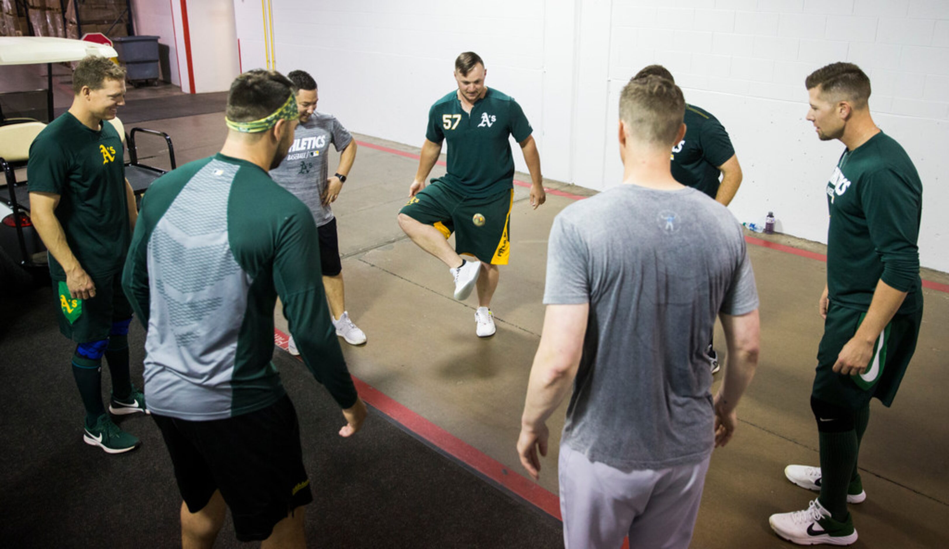 Oakland Athletics players play hacky sack in the tunnel during a rain delay at an MLB game...