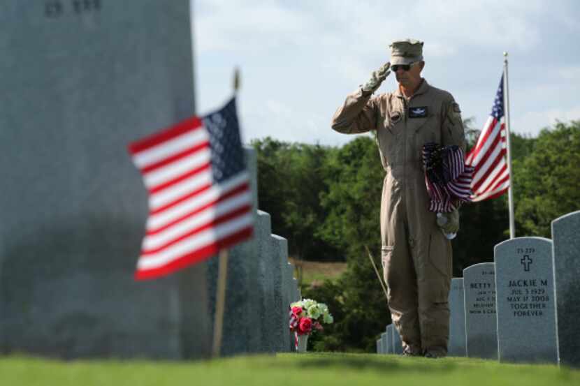 Retired Air Force Col. Roscoe Griffin saluted after placing a flag on a veteran's grave at...