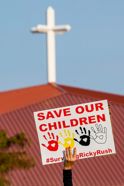 A demonstrator holds a sign for motorists entering the parking lot at a protest outside the...