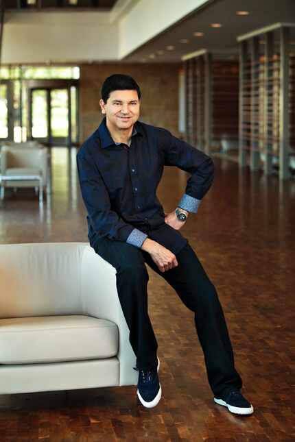 Capital One President Sanjiv Yajnik poses in a dark button-down shirt and jeans while...