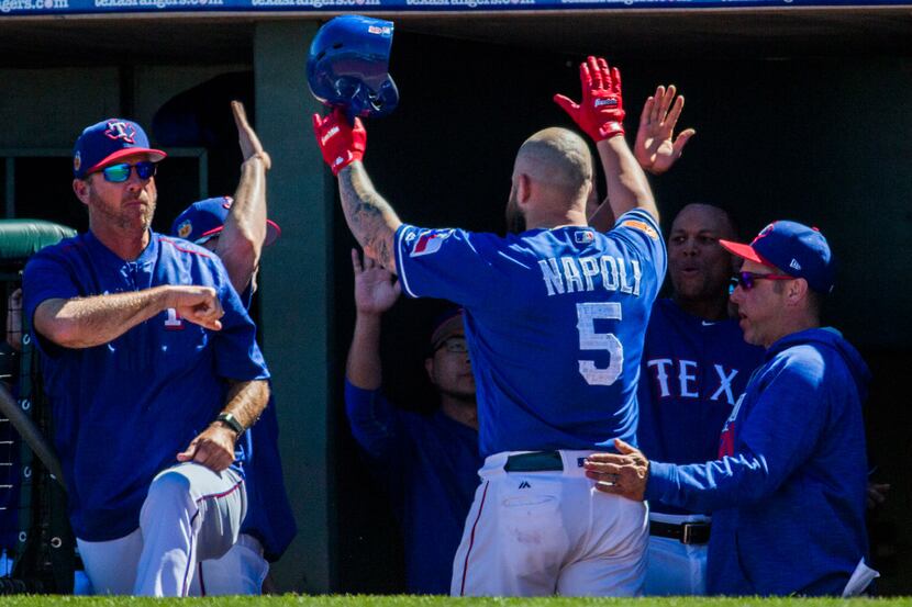 Texas Rangers first baseman Mike Napoli (5) gets high-fives from teammates in the dugout...