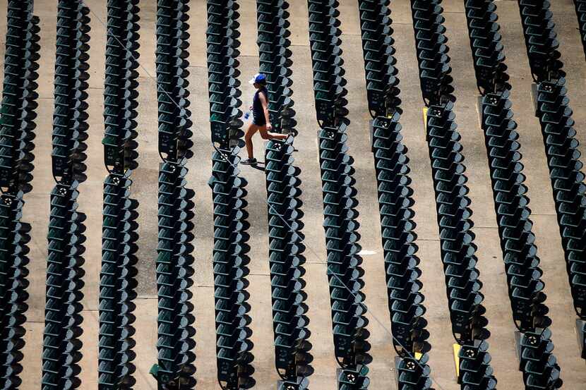 A lone girl walks past aisles of empty seats at Globe Life Park in Arlington during the...