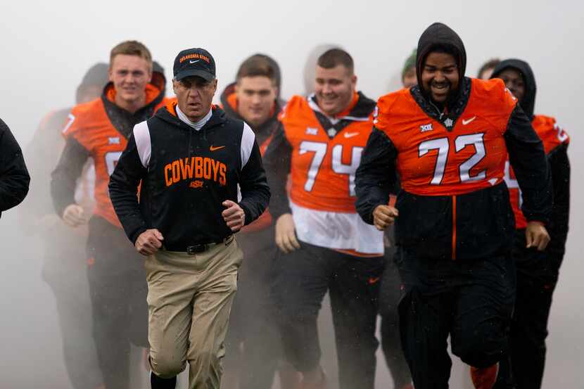 Oklahoma State head coach Mike Gundy leads injured players onto the field before the NCAA...
