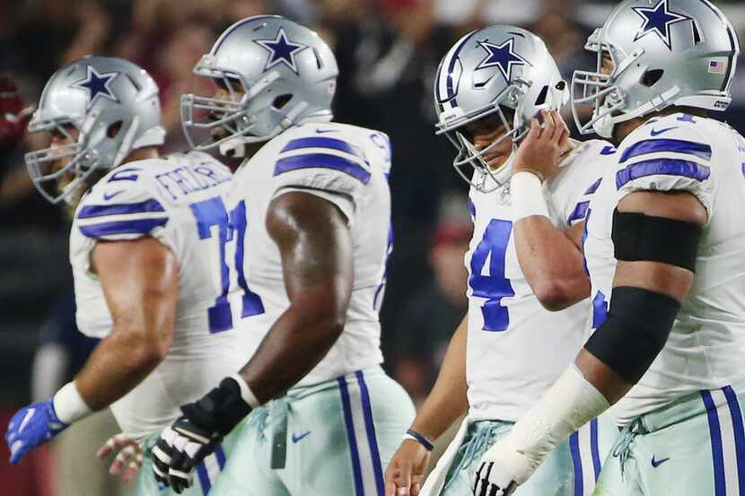 Dallas Cowboys quarterback Dak Prescott (4) walks off the field with teammates in the first...