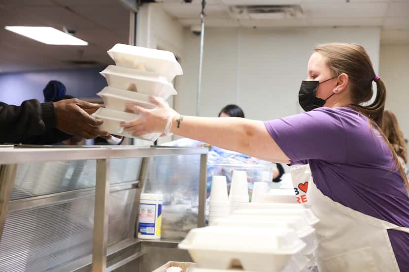 Heather Bruce hands a man four meals for his family, Friday, Nov. 18, 2022, at Annette G....