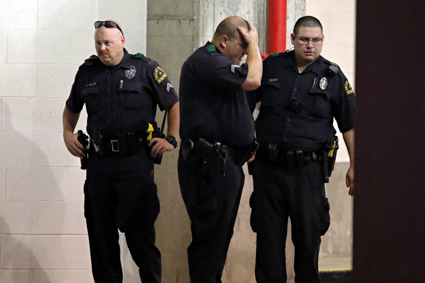 Dallas Police officers react  following a deadly shooting Friday, July 7, 2016 in Dallas. As...