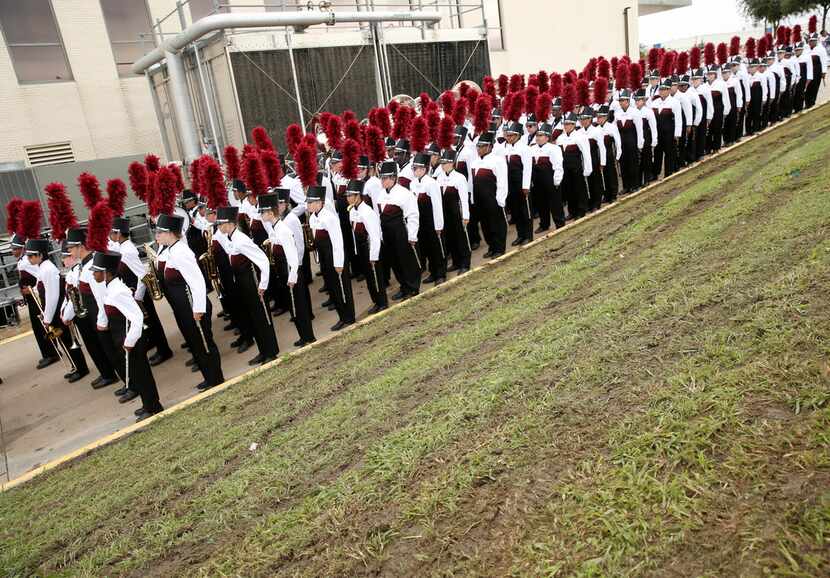The Red Oak Mighty Hawk Band waited next to freshly mowed, muddy grass before performing in...