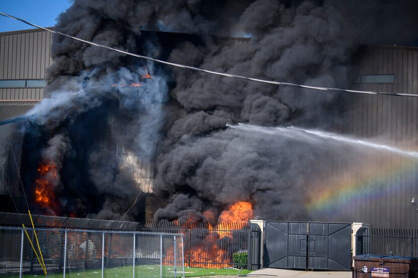 A fire truck sprayed water as flames erupted from a hangar at  Addison Airport on Sunday...