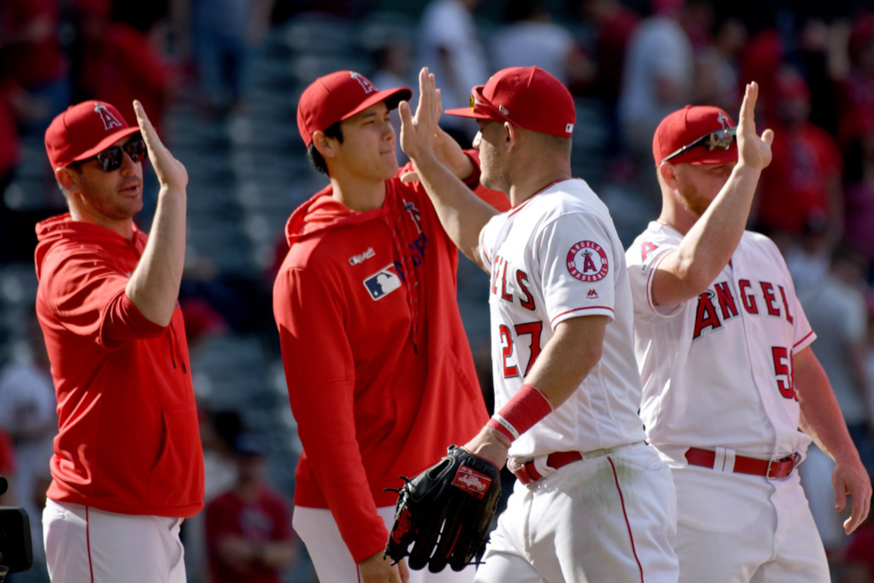 Los Angeles Angels' Mike Trout (27) high-fives with Shohei Ohtani, of Japan, second from...