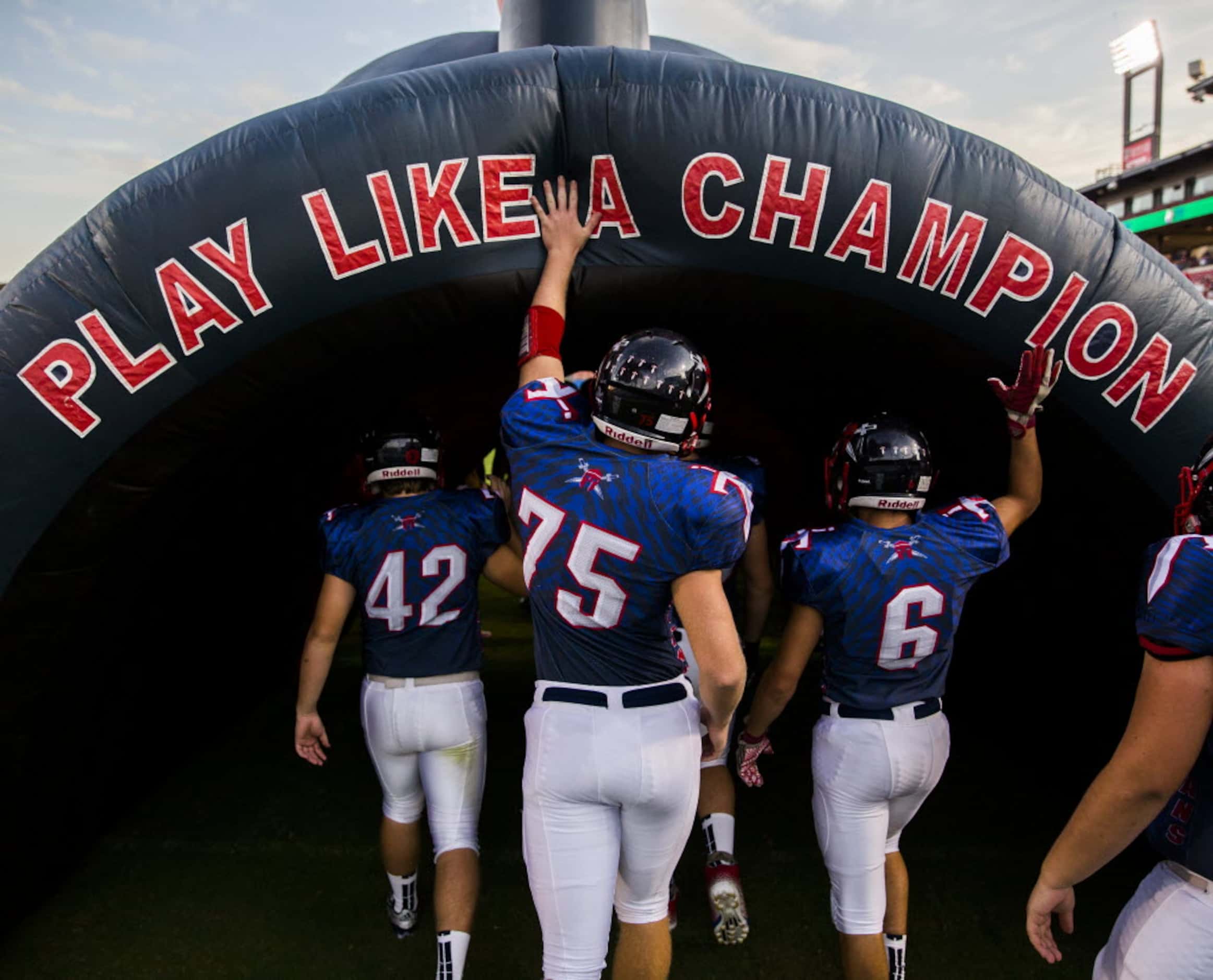 Frisco Centennial football players enter an inflatable tunnel before taking the field...