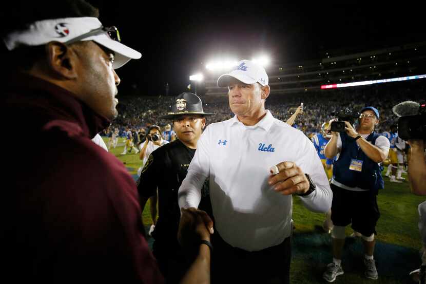 UCLA head coach Jim Mora, right, shakes hands with Texas A&M head coach Kevin Sumlin, left,...