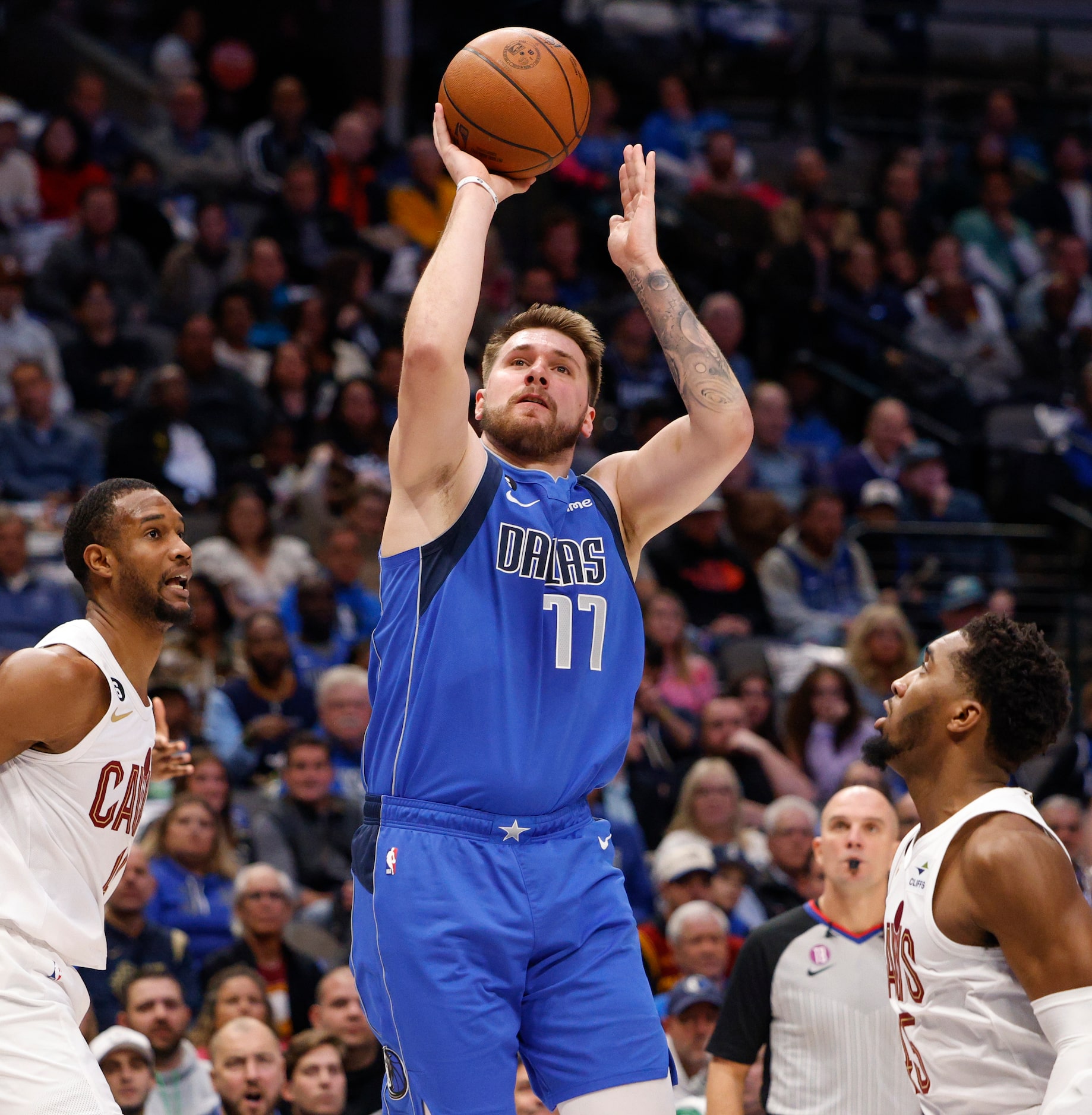 Dallas Mavericks guard Luka Doncic (77) shoots the ball between Cleveland Cavaliers forward...