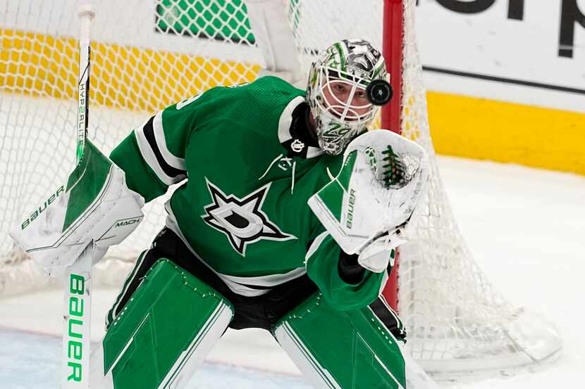Dallas Stars goaltender Jake Oettinger reaches up to glove a shot from the Minnesota Wild...