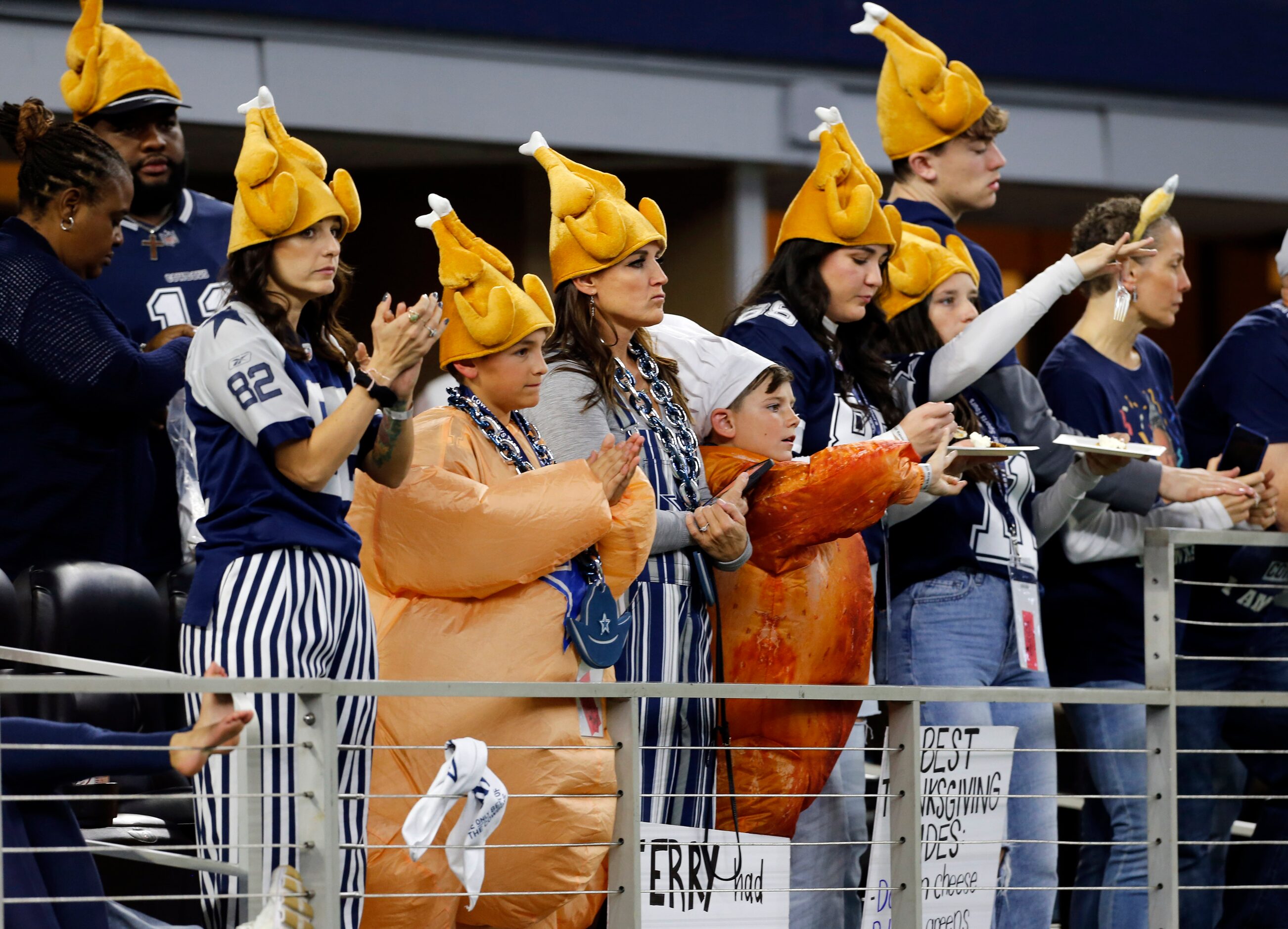 Fans in turkey hats cheer from the sidelines during the first half of a NFL football game...