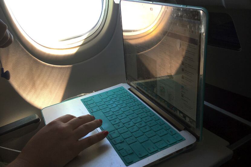 In this July 1, 2017, photo, a passenger uses a laptop aboard a commercial airline flight...
