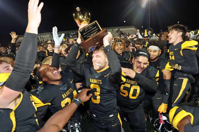 Forney quarterback Kyle Crawford (3) holds the trophy high as he and his teammates celebrate...
