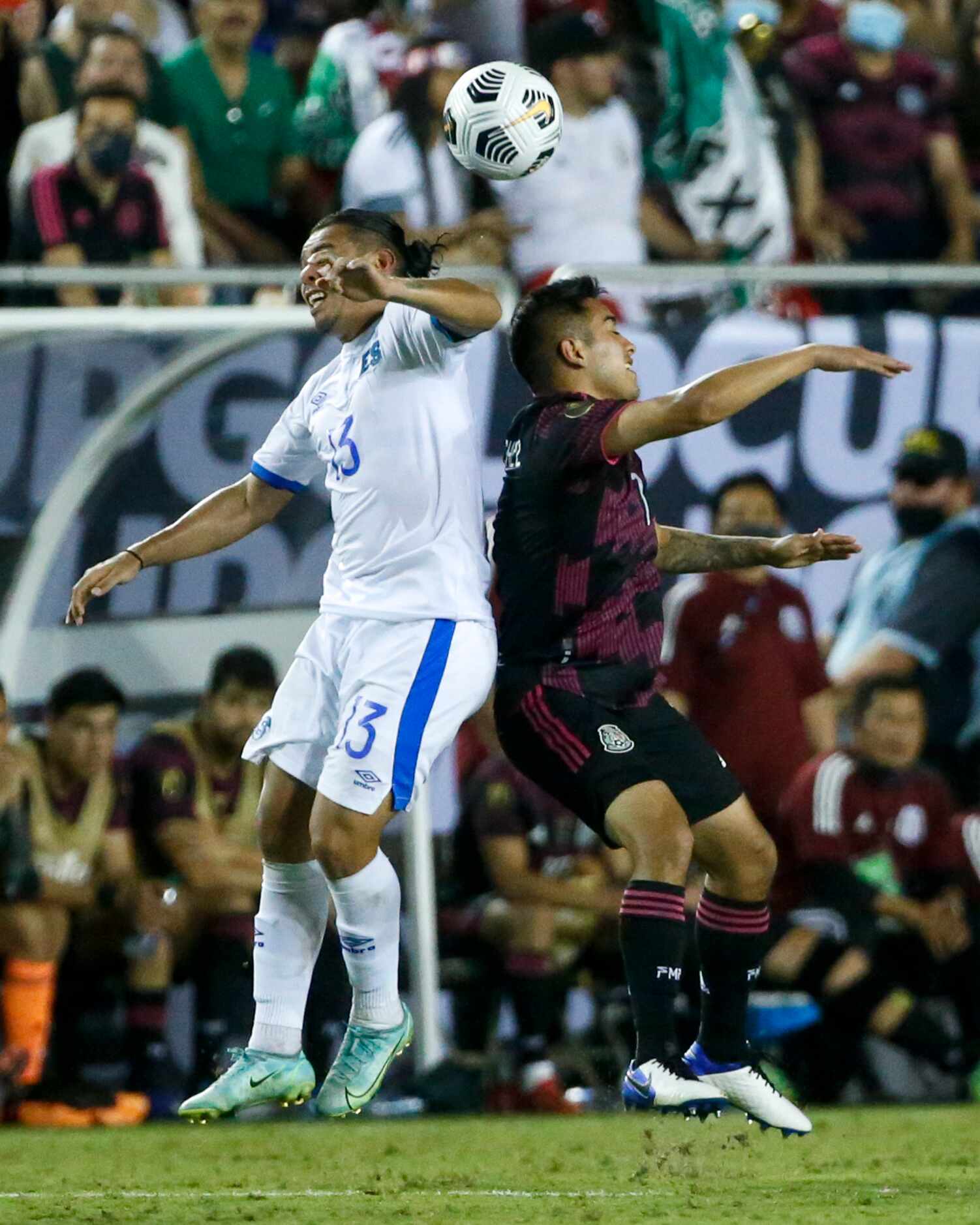 El Salvador defender Alexander Larín (13) and Mexico forward Erick Sánchez (7) leap to head...