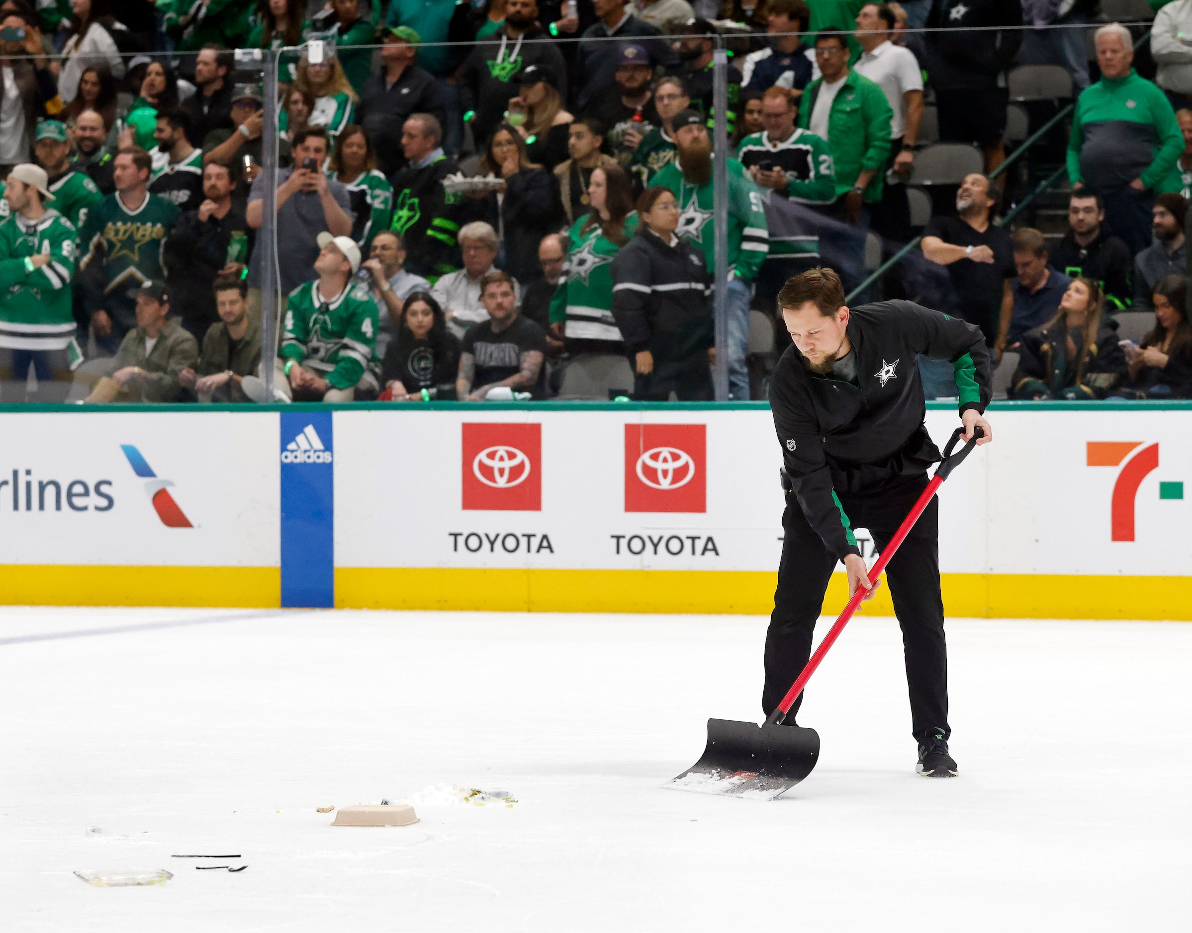 A Dallas Stars ice crew member shovels up debris thrown on the ice by fans following a...