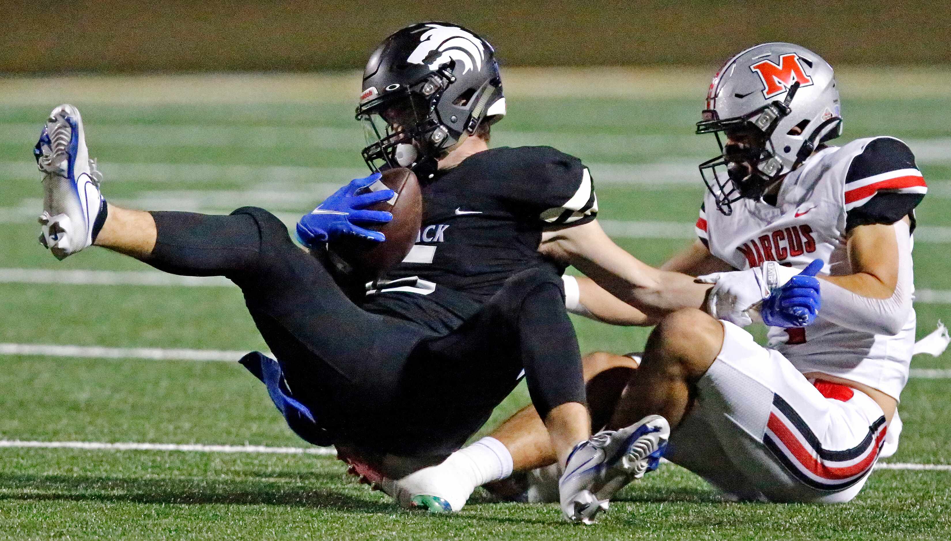 Plano West High School wide receiver Jackson Stambaugh (15) is swung to the ground by Flower...