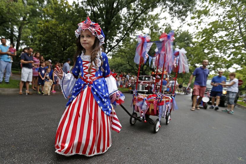 Roselyn Halvorson, 6, waves to the crowd as she participates in the Lakewood Fourth of July...