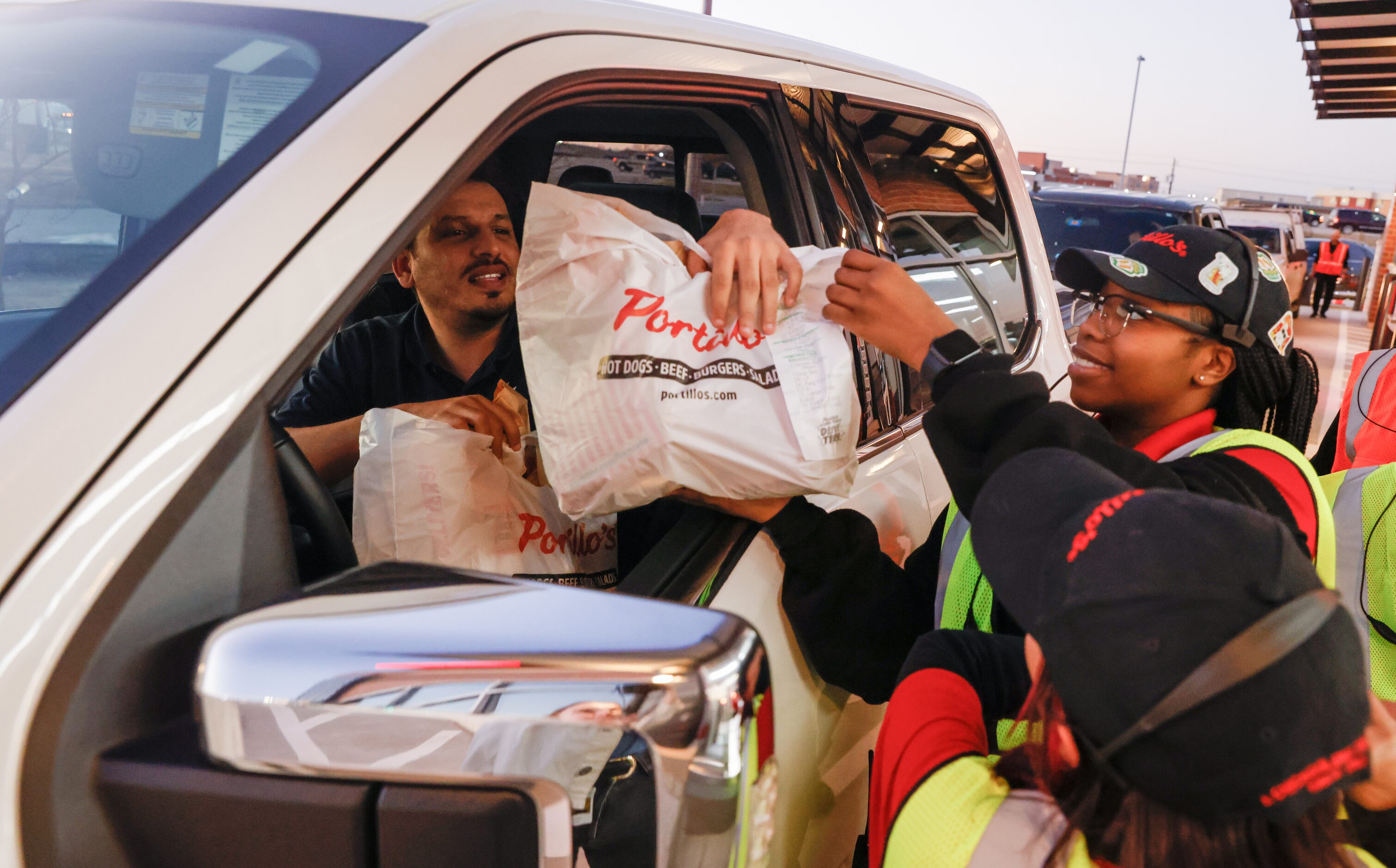 Ryan Evans (left) takes his Portillo’s order from Fadzai Murombedzi (right) in the...