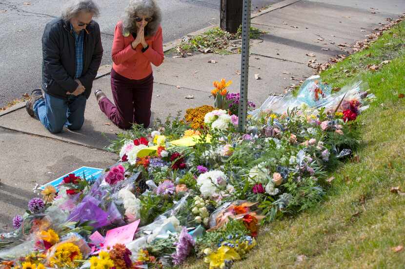 A couple kneels before a memorial at Murray and Wilkins avenues on Sunday, Oct. 28, 2018 in...