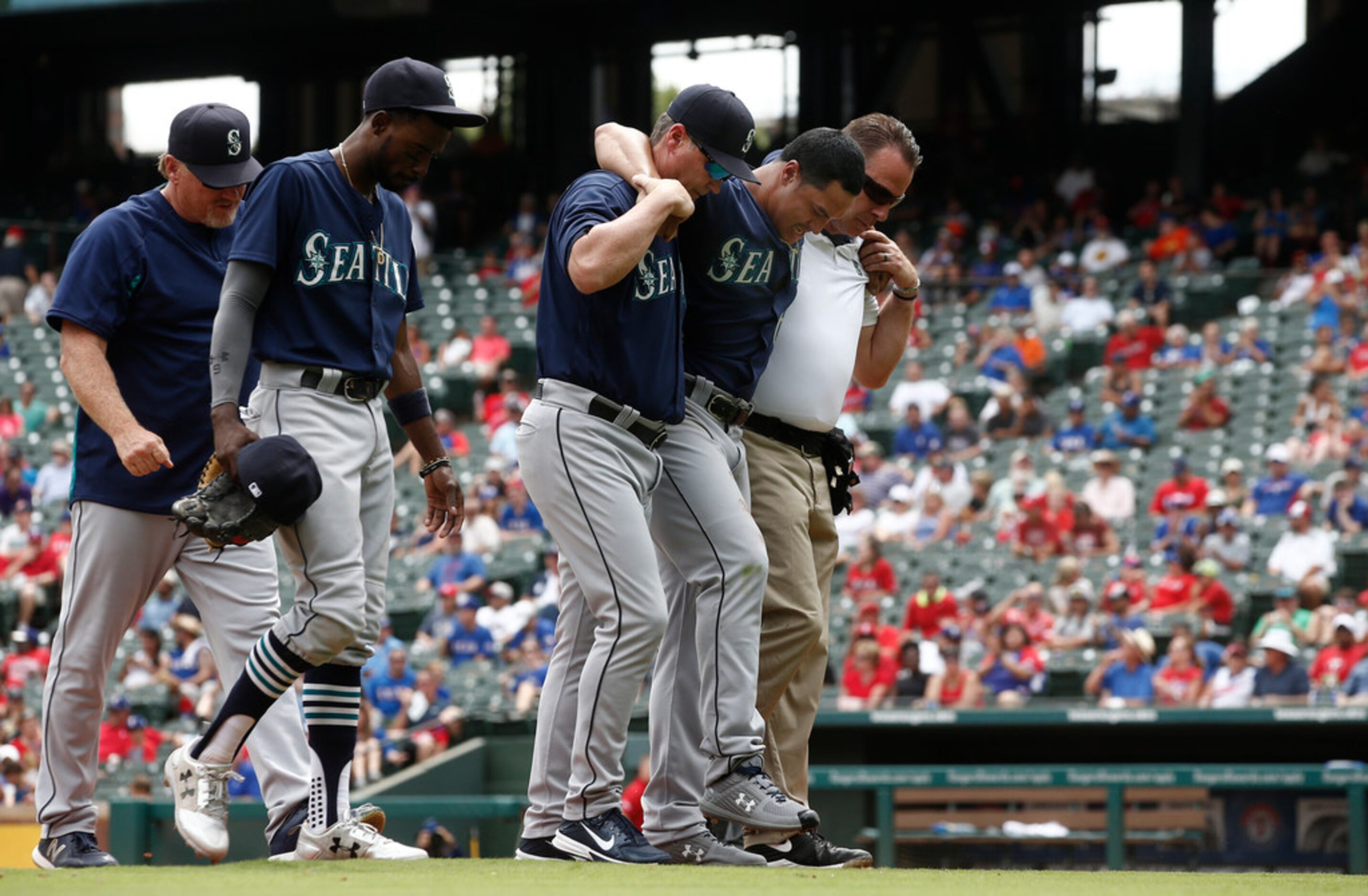 Seattle Mariners pitcher Sam Tuivailala is helped off the field by manager Scott Servais...