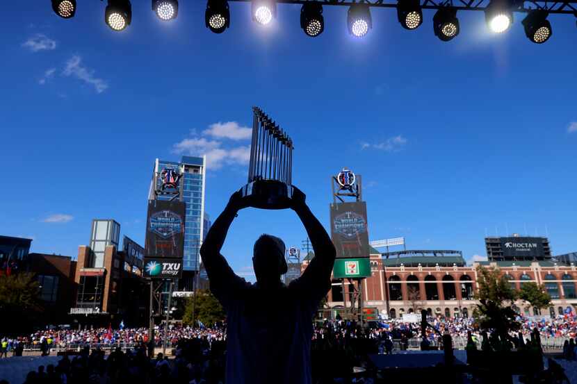 Texas Rangers left fielder Evan Carter hoists the Commissioner's Trophy for a family photo...