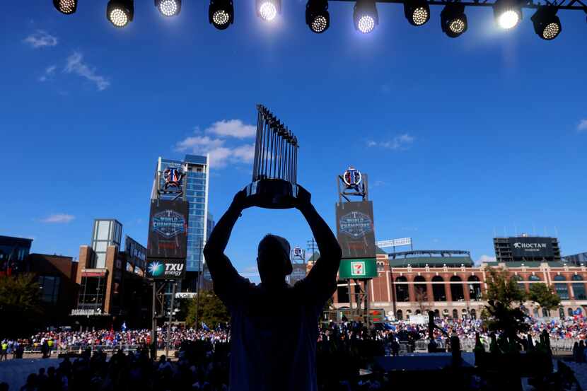 Texas Rangers left fielder Evan Carter hoists the Commissioner's Trophy for a family photo...