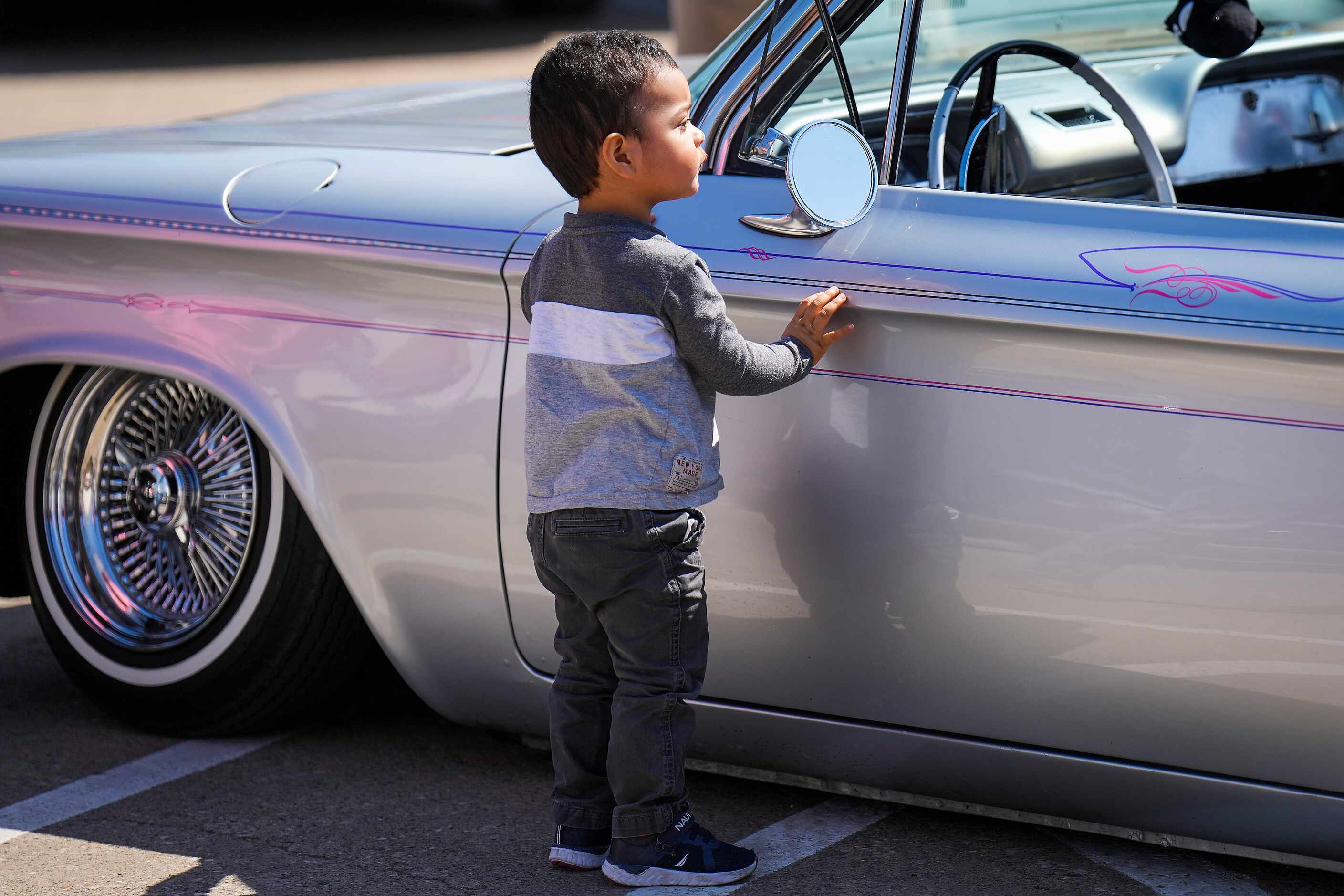 A youngster checks out a car on display from the Dallas Lowriders car club during the...