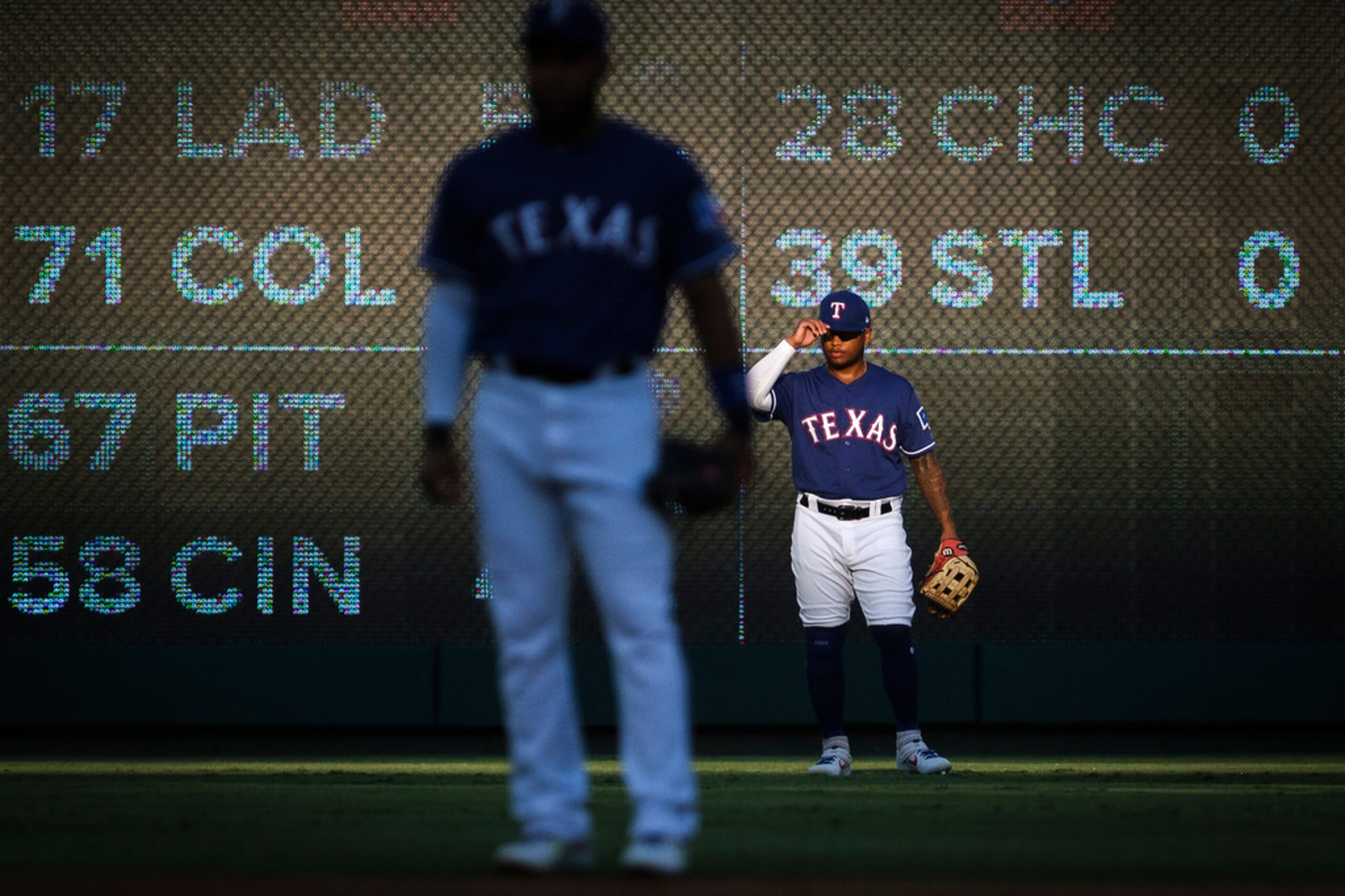 Texas Rangers left fielder Willie Calhoun lines up in the sun behind shortstop Elvis Andrus...