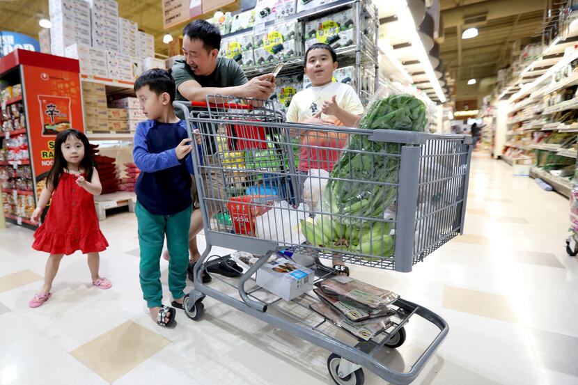 A family shops at H Mart in Carrollton, Texas, Tuesday April 19, 2022. From left are Ellie...