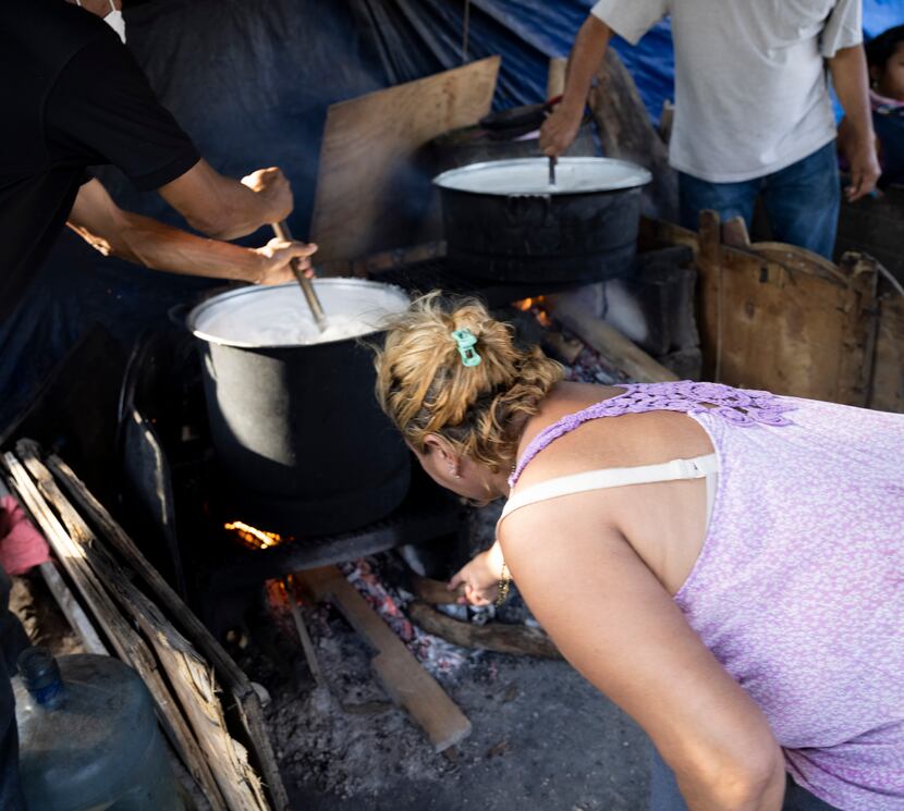 Leticia Hernandez refuels the fire as other migrants prepare two batches of arroz con leche...