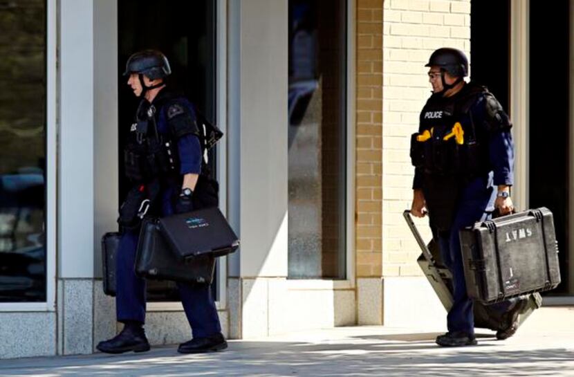 
Police officers carried cases as they entered a building during a standoff with an armed man.
