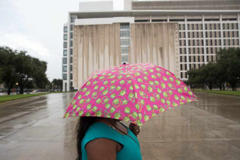 A pedestrian walks with an umbrella passing the John F. Kennedy Memorial Plaza during the...