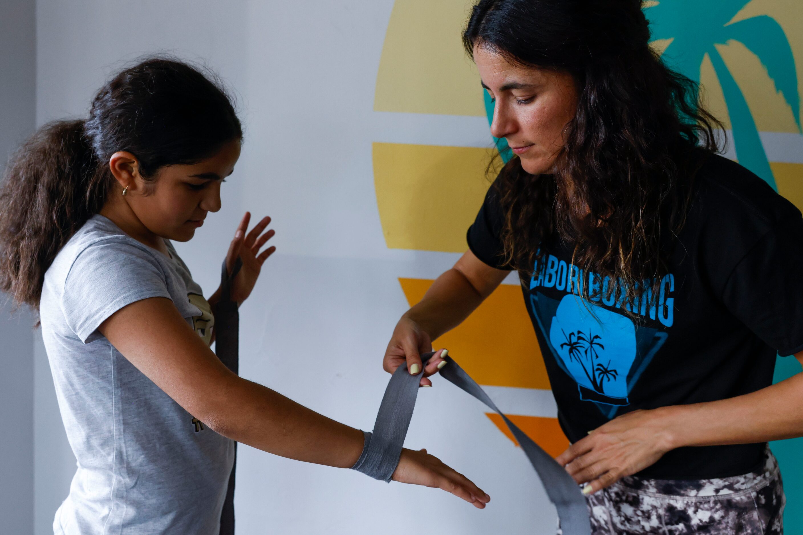 Amanda Alvarez, a salsa teacher and boxing lover, helps wrapping Bri Flores (left) before a...