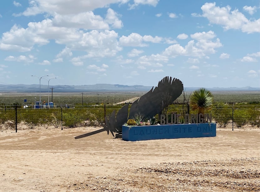 A freshly-painted sign reads Blue Origin, Launch Site One, with a trademark feather, which...