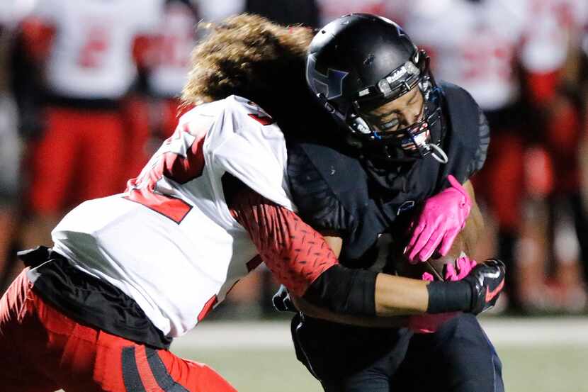 Euless Trinity free safety Sebastian Tauaalo (32) tackles Hebron wide receiver Nigel Blount...