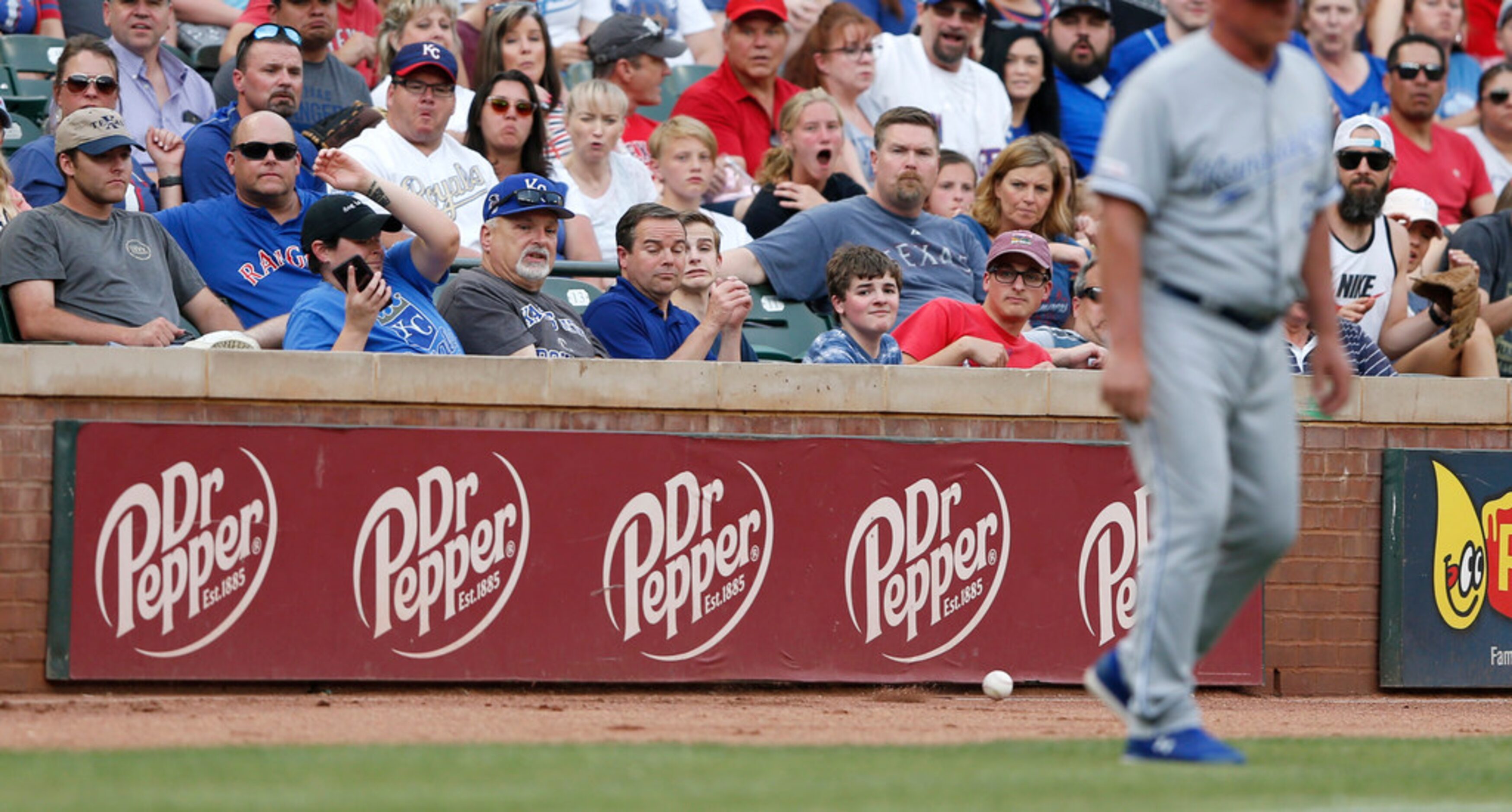 Fans react as a foul ball comes their way in a game between the Texas Rangers and Kansas...