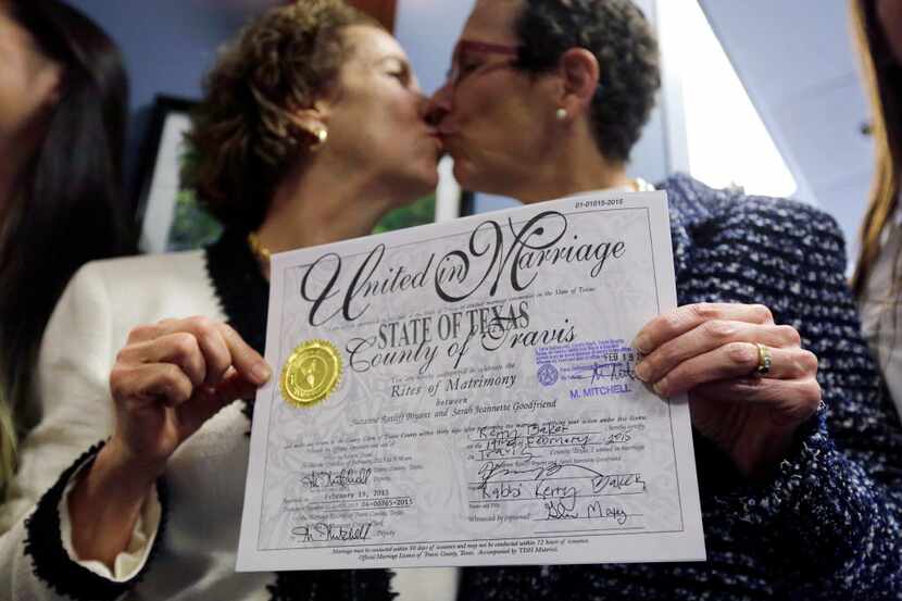 Suzanne Bryant, left, and Sarah Goodfriend, right, exchange a kiss as they pose for a...