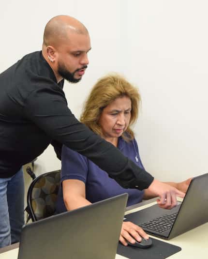 Man helps a woman work on her laptop