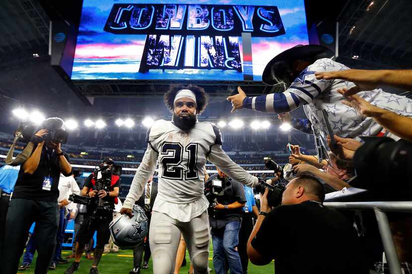 Dallas Cowboys running back Ezekiel Elliott (21) slaps hands with fans after their win over...