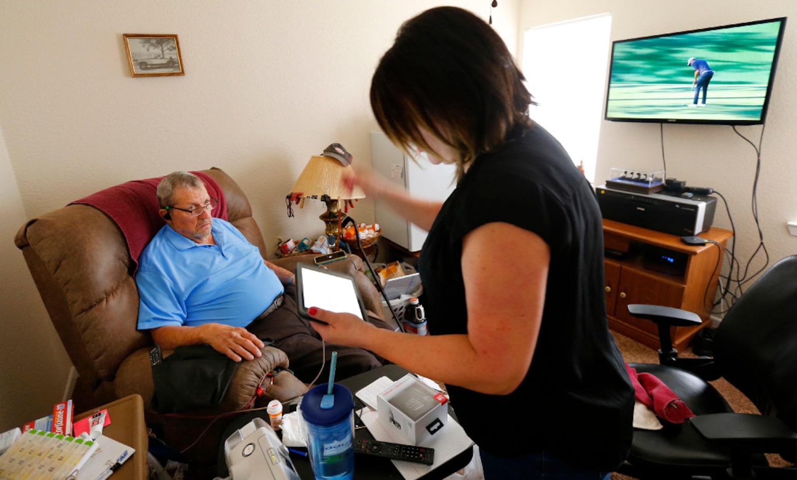 Former Dallas Cowboy George Andrie tries to connect a new pair of bluetooth ear buds with...